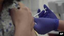 Screen grab taken from video issued by Oxford University, showing a person being injected as part of the first human trials in the UK to test a potential coronavirus vaccine, undertaken in England, April 23, 2020. 