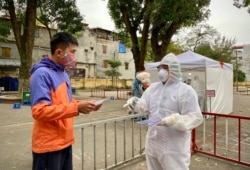 A health worker in protective gear talks to a man as she gives him his COVID-19 test result at a makeshift testing facility in Hanoi, Vietnam on March 31, 2020.
