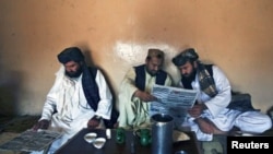 Pashtun men read local newspapers reporting the arrest of senior al Qaeda leader Younis al- Mauritani at roadside tea shop in Quetta.