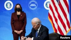 El presidente Joe Biden, junto con la vicepresidenta Kamala Harris, firma una orden ejecutiva en la Casa Blanca, el 25 de enero de 2021.