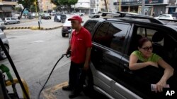 Archivo. En esta imagen del 23 de marzo de 2017 un empleado bombea gasolina para un cliente en una gasolinera en Caracas, Venezuela. 