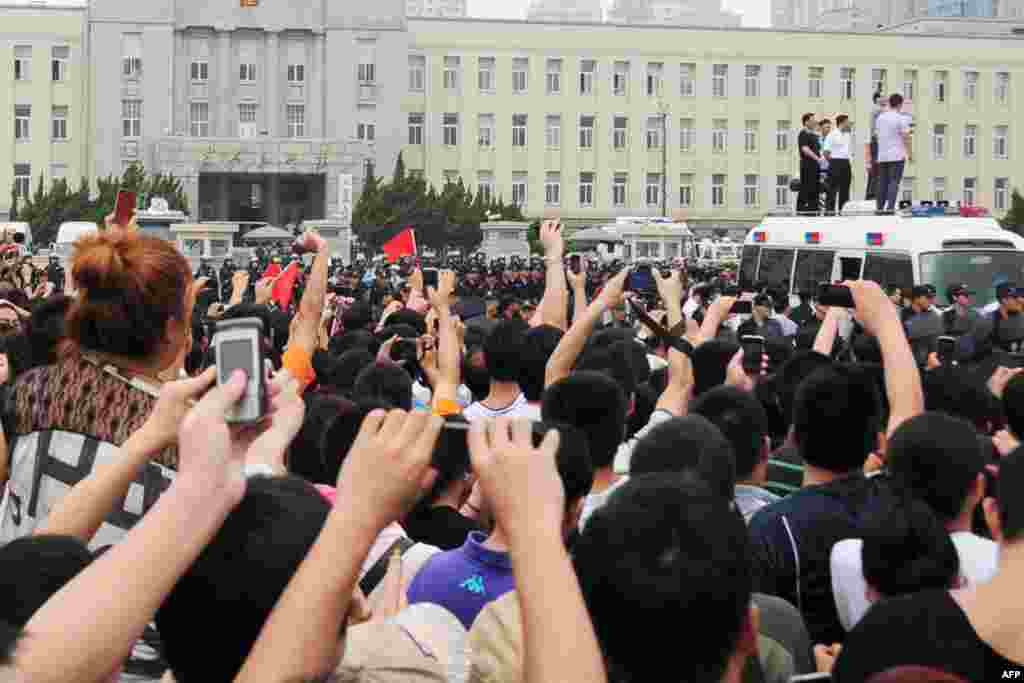 Nhiều người dùng điện thoại di động chụp cảnh đại diện chính quyền nói chuyện với người biểu tình ở nhà máy Đại Liên. (Reuters)