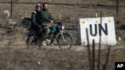 Archivo - En esta fotografía de noviembre de 2016, dos hombres conducen una moticicleta hacia una base abandonada de la ONU en la frontera de Quneitra entre Siria y los Altos del Golán.