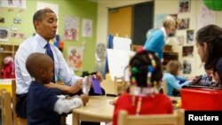 U.S. President Barack Obama reads a card during a game with children in a per-kindergarten classroom at College Heights early childhood learning center in Decatur, Georgia, February 14, 2013. 