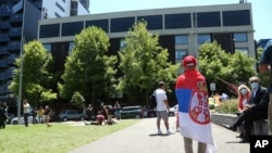 A fan of Serbia's Novak Djokovic stands outside the Park Hotel, used as an immigration detention hotel where the world's No. 1-ranked tennis player is detained in Melbourne, Australia, Jan. 9, 2022. 