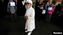 A man stands near supporters of Muslim Brotherhood and ousted Egyptian President Mohamed Morsi as they shout slogans against the military and the interior ministry during a protest in front of Al Tawheed mosque in Cairo, Aug. 23, 2013.