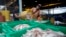 FILE - Migrant workers separate freshly caught fish by size at a fish market in Samut Sakhon Province, west of Bangkok, June 20, 2014.