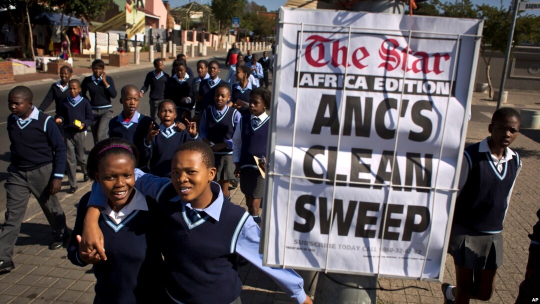 Des enfants marchent près d'une Une de journal après la victoire de Jacob Zuma de l'ANC, à Johannesburg, Afrique du sud, le 9 mai 2014.