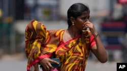 FILE - A woman covers a child using a part of her sari to shield from the sun on a hot summer day in Hyderabad, India, April 30, 2024.