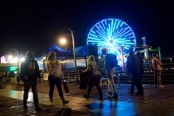 Visitors wear face masks while walking the pier amid the COVID-19 pandemic Feb. 19, 2021, in Santa Monica, Calif.