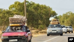 Families fleeing from the fighting between pro-Gaddafi and anti-Gaddafi forces drive pass Khamseen Gate, 50 km (31.1 miles) east of Sirte, October 1, 2011.