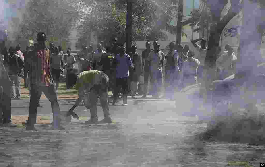Supporters of President Abdoulaye Wade retreat from tear gas, fired by security forces, outside the polling station where Wade was due to vote, March 25, 2012. (AP)