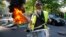 A man bangs a drum in front of a fire on the street during a yellow vest demonstration in Paris, Apr. 20, 2019. 