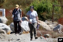 Taormina Lepore (depan), yang memiliki keterbatasan penglihatan, berjalan dengan tongkat putih saat kunjungan lapangan yang dapat diakses di San Bernadino, California, 26 September 2024. (Ryan Sun/AP)