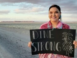 Jaden Williams, former Miss Southwest Navajo 2017-2018, poses with a sign encouraging fellow Navajo (Dine) citizens to remain strong during the COVID-19 epidemic.