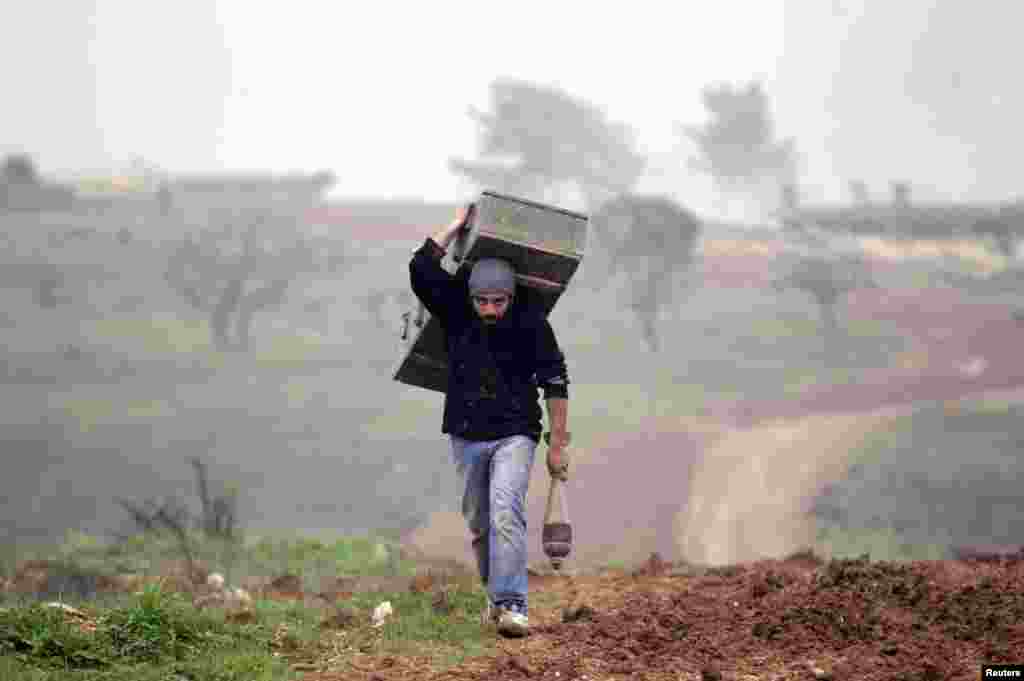 A man carries a weapon box left behind by forces loyal to Syria&#39;s President Bashar al-Assad at the Azaalana checkpoint in the southern Idlib countryside, Dec. 20, 2014.