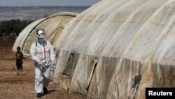 FILE - A member of the Syrian Civil Defense sanitizes a tent at the Bab Al-Nour internally displaced persons camp, to prevent the spread of coronavirus disease (COVID-19) in Azaz, Syria, March 26, 2020..