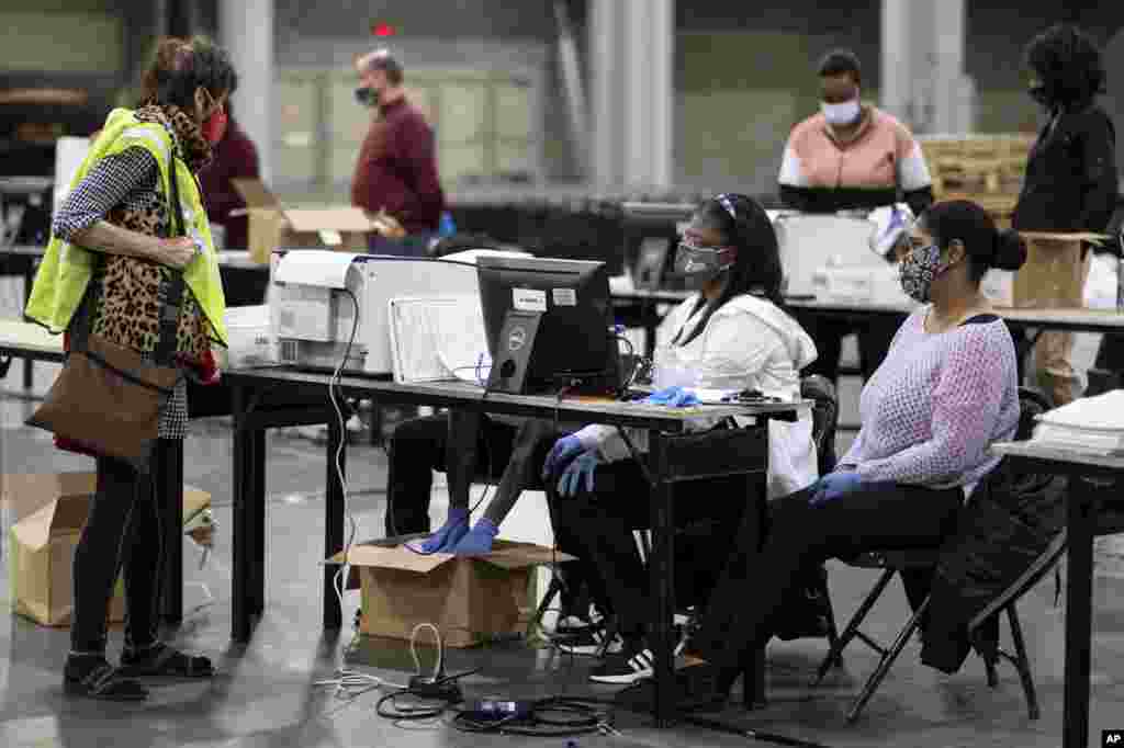 A GOP observer, left, watches as workers scan ballots as the Fulton County presidential recount gets under way at the Georgia World Congress Center in Atlanta.