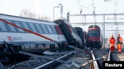 Dua orang anggota tim penyelamat berdiri di dekat kereta api pasca tabrakan di wilayah Rafz, sekitar 30 kilometer dari Zurich, Siwss (20/2). 