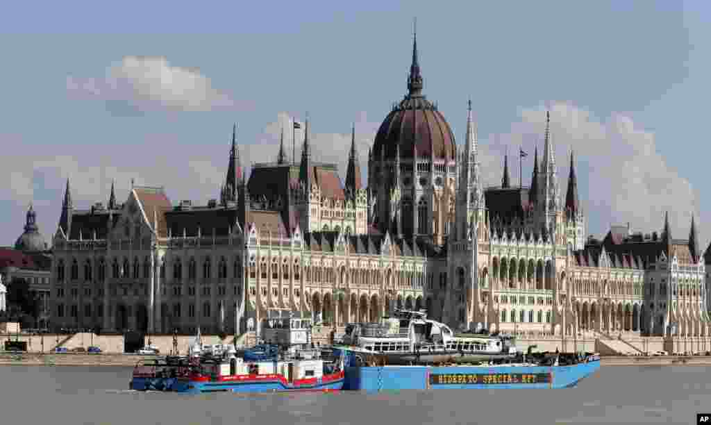 A barge carries the sightseeing boat, right, past the house of parliament on the Danube river after it was lifted from riverbed in Budapest, Hungary. Four people are still missing from the May 29 collision between the Hableany (Mermaid) sightseeing boat and the Viking Sigyn river cruise ship near to Budapest&#39;s Margit Bridge.