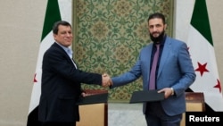 Syria's interim President Ahmed al-Sharaa, right, and commander of Syrian Kurdish-led forces Mazloum Abdi shake hands after reaching a ceasefire and military deal in Damascus, on March 10, 2025. (SANA/Handout via Reuters)