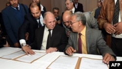 FILE - Awad Mohammed Abdul-Sadiq (L), of the Tripoli-based General National Congress (GNC), and Ibrahim Fethi Amish, from the internationally recognized House of Representatives, sign agreement on ending the political deadlock in Libya, Dec. 6, 2015.