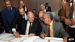 Awad Mohammed Abdul-Sadiq, du Parlement de Tripoli, et Ibrahim Fethi Amish du Parlement reconnu par la communauté internationale, signent un accord, le 12 décembre 2015. (AFP PHOTO / FETHI BELAID / AFP / FETHI BELAID)