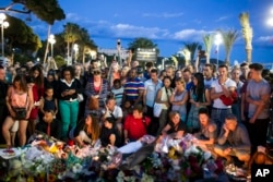 People gather at a makeshift memorial to honor the victims of an attack, near the area where a truck mowed through revelers in Nice, southern France, Friday, July 15, 2016.