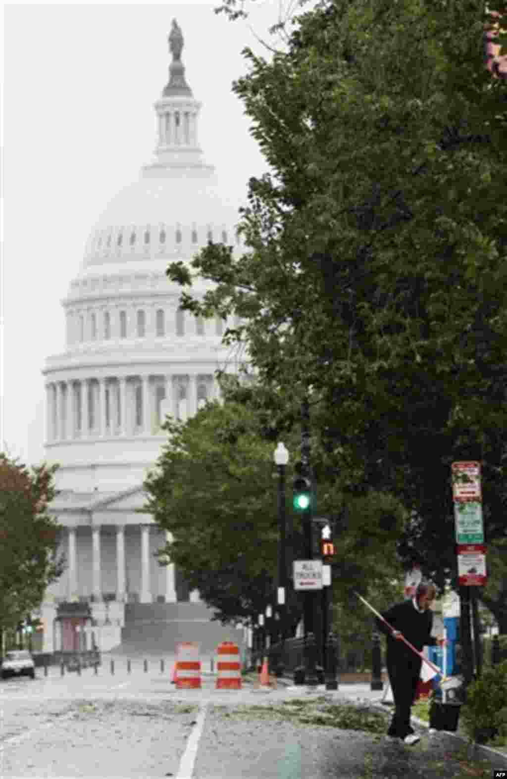 An unidentified man is seen cleaning debris from the curb in the Capitol Hill neighborhood of Washington, the morning after Hurricane Irene moved through the city, Sunday, Aug., 28, 2011. (AP Photo/Pablo Martinez Monsivais)