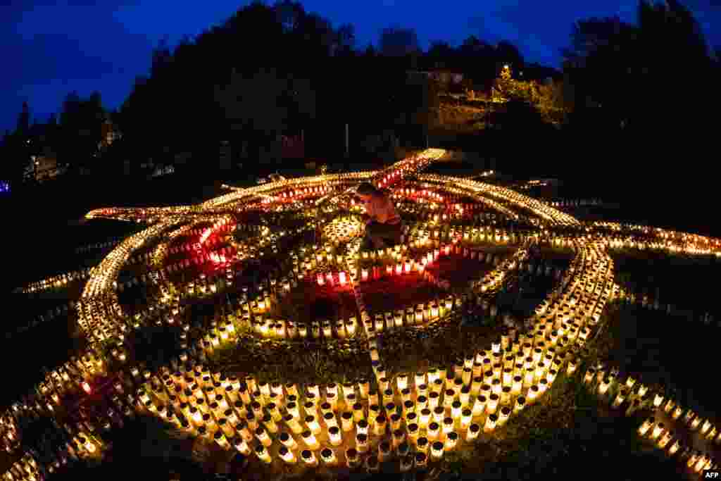 Sixty-year-old Gertrud Schop lights candles that form the shape of a cross, with one candle honoring each of the more than 8,000 Germans who have died from the new coronavirus, in Zella-Mehlis, eastern Germany.