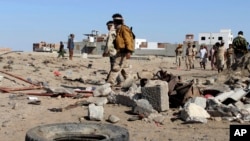 Beberapa tentara Yaman memeriksa lokasi serangan bunuh diri yang menewaskan puluhan rekan mereka di Aden, Minggu (18/12).