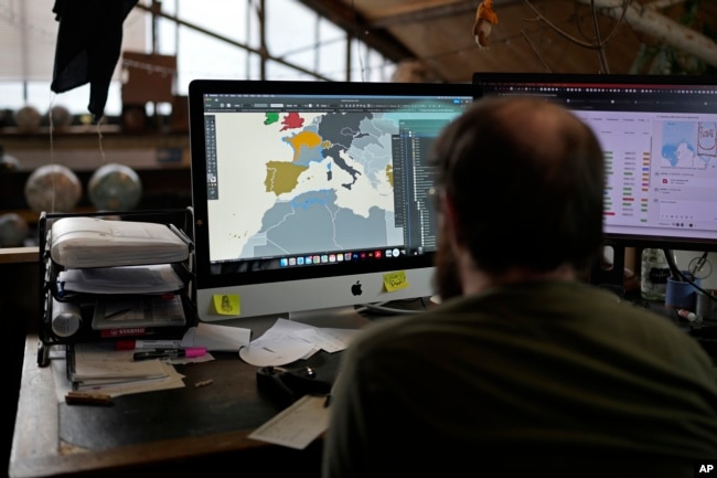 An artist uses computer to create a map at a studio in London, Tuesday, Feb. 27, 2024. Globes in the age of Google Earth capture the imagination and serve as snapshots of how the owners see the world and their place in it. (AP Photo/Kin Cheung)