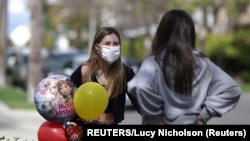 Une femme nommée Lily Haines (G) discute avec son amie, Ella Davis, tout en respectant la distance sociale; alors que la propagation de la maladie à coronavirus (COVID-19) continue, à Los Angeles, Californie, États-Unis, le 8 avril 2020. REUTERS / Lucy Nicholson