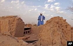 In this Friday, April 4, 2014, file photo, head mason Alassane Ramiya inspects the remains of tombs at a mausoleum after it was damaged in Timbuktu, Mali.