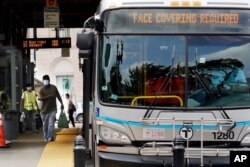 FILE- In this June 24, 2020, file photo, a man, wearing a protective face mask, rushes to catch his bus at Dudley Station in Nubian Square in Boston. Face coverings are required on all buses, subways, trains and trolleys in Boston due to the COVID…