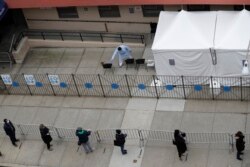 People stand in line as they wait to get tested for COVID-19 at a just opened testing center in the Harlem section of New York, Monday, April 20, 2020.