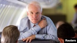 Arizona Senator and Republican presidential hopeful John McCain looks up while speaking with his campaign manager Rick Davis, left, and national political director John Weaver during a flight from South Carolina to California Feb. 4, 2000.
