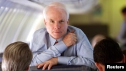 Arizona Senator and Republican presidential hopeful John McCain looks up while speaking with his campaign manager Rick Davis, left, and national political director John Weaver during a flight from South Carolina to California Feb. 4, 2000.