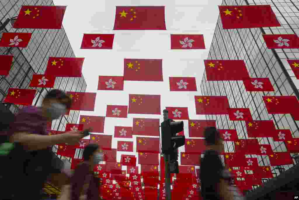 People walk past China national flags and Hong Kong flags for the celebration of 24th anniversary of Hong Kong handover to China in a shopping district.