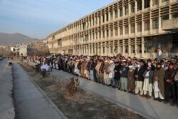 Penduduk desa melakukan shalat di dekat peti jenazah Mohammad Yousuf Rasheed, semeblum dimakamkan di Kabul, Afghanistan, Rabu, 23 Desember 2020.