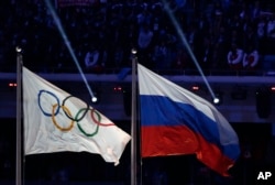 FILE - The Russian national flag (R) flies next to the Olympic flag during the closing ceremony of the 2014 Winter Olympics in Sochi, Russia, Feb. 23, 2014.