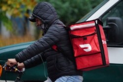 Seorang pengantar makanan Doordash mengendarai sepedanya di tengah hujan saat pandemi COVID-19 di wilayah Manhattan, New York City, New York, AS, 13 November 2020. (REUTERS/Carlo Allegri)