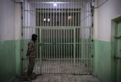 A member of the Syrian Democratic Forces (SDF) stands guard in a prison where men suspected to be afiliated with the Islamic State are jailed in northeast Syria in the city of Hasakeh on Oct. 26, 2019.