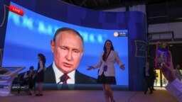 Peserta berkumpul di dekat layar yang memperlihatkan Presiden Rusia Vladimir Putin, yang menyampaikan pidato di Forum Ekonomi Internasional St. Petersburg (SPIEF) di Saint Petersburg, Rusia, 17 Juni 2022. (Foto: REUTERS/Anton Vaganov)