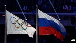 FILE - The Russian national flag, right, flies next to the Olympic flag during the closing ceremony of the 2014 Winter Olympics in Sochi, Russia, Feb. 23, 2014. 