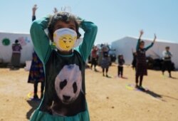 A displaced girl wears a face mask provided by the Violet Organization, in an effort to spread awareness and encourage safety amid coronavirus disease fears, at a camp near Maarat Masrin in northern Idlib, Syria April 14, 2020.