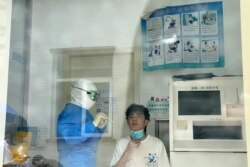 In an image shot through glass, a resident waits to get tested at a fever clinic in Beijing, China, June 15, 2020.