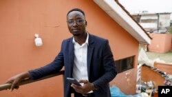 FILE—Shadrach Damateye, a co-founder of Masters Hive Center for Innovation, who uses his mobile phone to help business owners, poses for a photograph outside his office in Tema, Ghana, April 23, 2024.