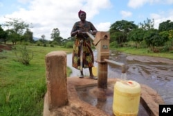 FILE—Rhoda Peter fills containers with water from a sand dam in Makueni County, Kenya on March 1, 2024.