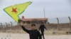 FILE - A Syrian Kurd waves the flag of YPG (People's Protection Units) near Qamishli's airport in northeastern Syria on December 8, 2024, following the fall of the capital Damascus to anti-government fighters.